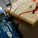 Fotografía de un arduino conectado a una protoboard sobre una mesa.