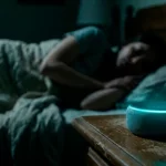 Persona durmiendo y a su lado sobre una mesa de noche un alexa.