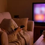 Mujer recostada en un sofa viendo la television.